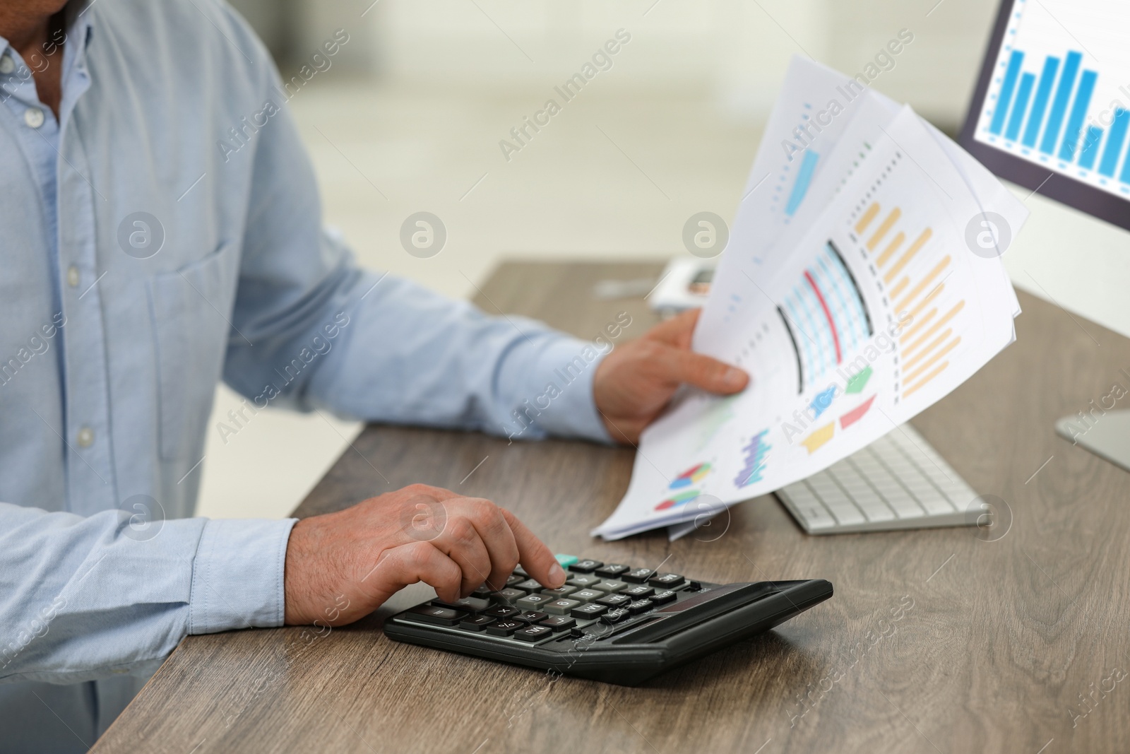 Photo of Professional accountant using calculator at wooden desk, closeup