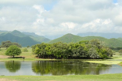 Photo of Picturesque view of mountains and green meadow with lake