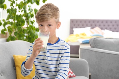 Adorable little boy with glass of milk at home