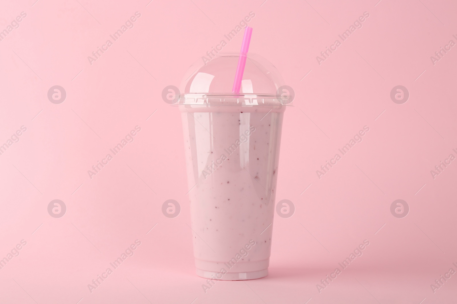 Photo of Plastic cup of tasty smoothie on pink background