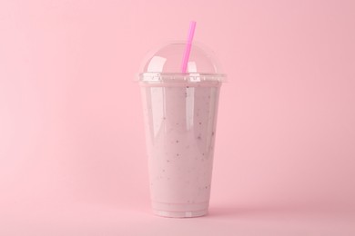 Photo of Plastic cup of tasty smoothie on pink background