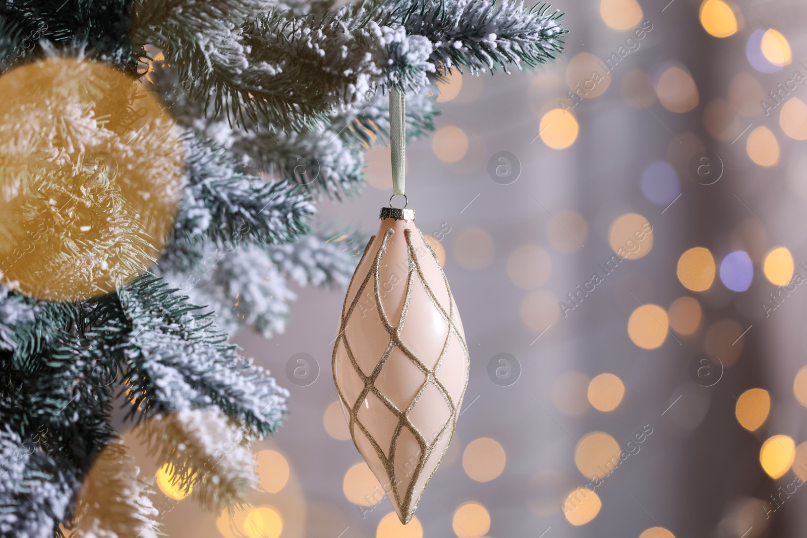 Photo of Christmas tree decorated with holiday bauble against blurred lights, closeup