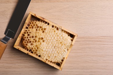Photo of Honeycomb frame and uncapping knife on wooden table, flat lay with space for text. Beekeeping tools