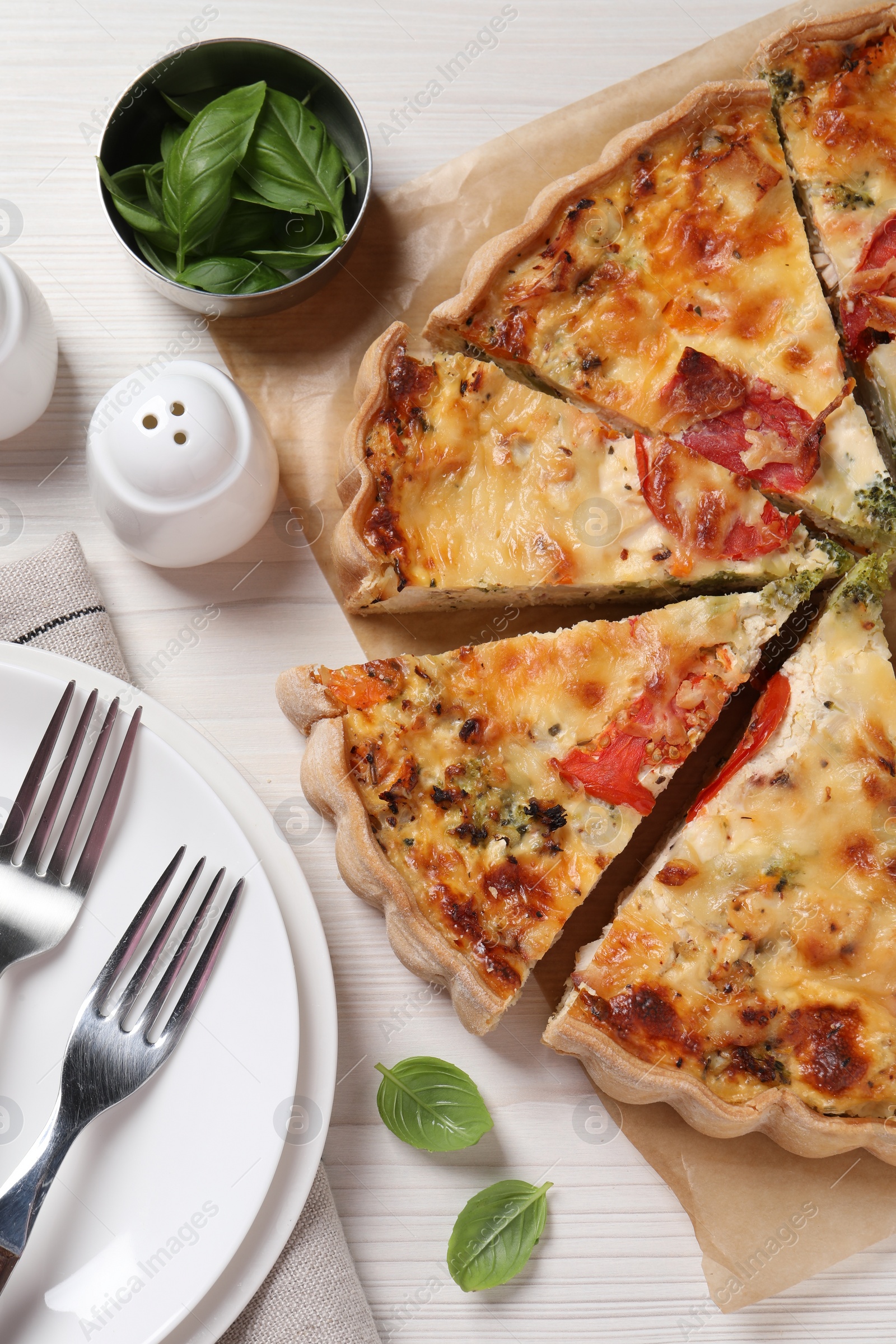 Photo of Tasty quiche with tomatoes and cheese served on white wooden table, flat lay