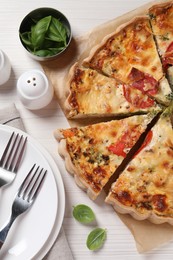 Photo of Tasty quiche with tomatoes and cheese served on white wooden table, flat lay