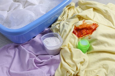 Photo of Dirty garment near basin with detergent foam, closeup. Hand washing laundry