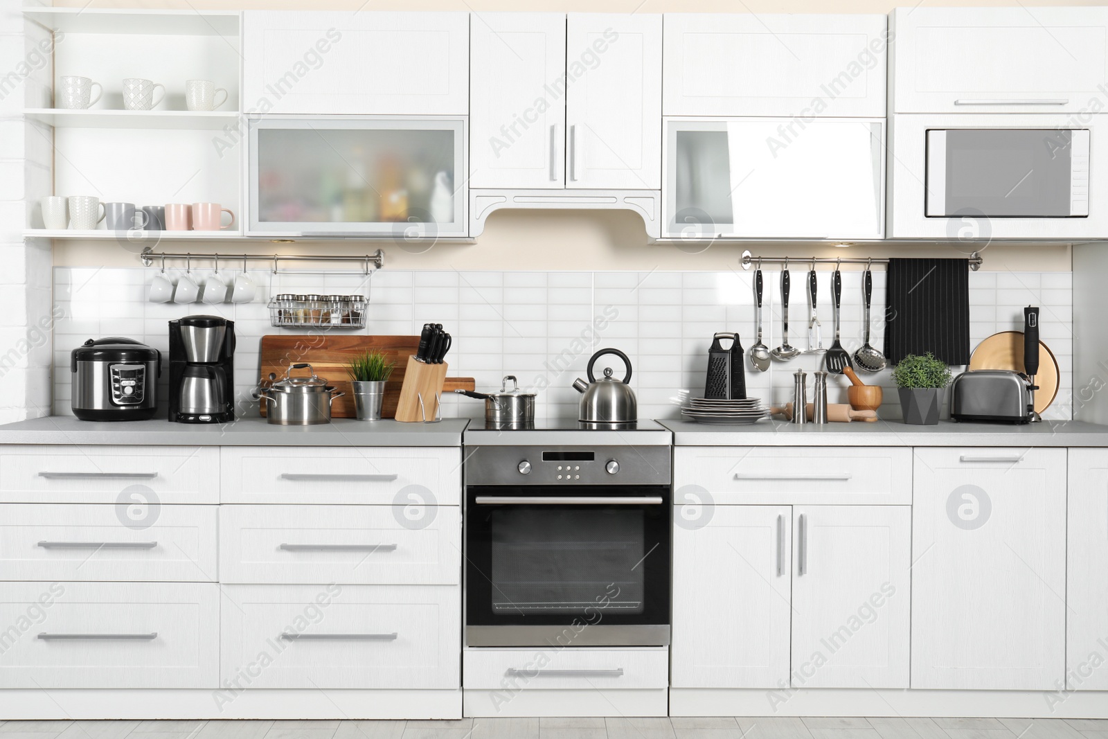 Photo of Different appliances, clean dishes and utensils on kitchen counter