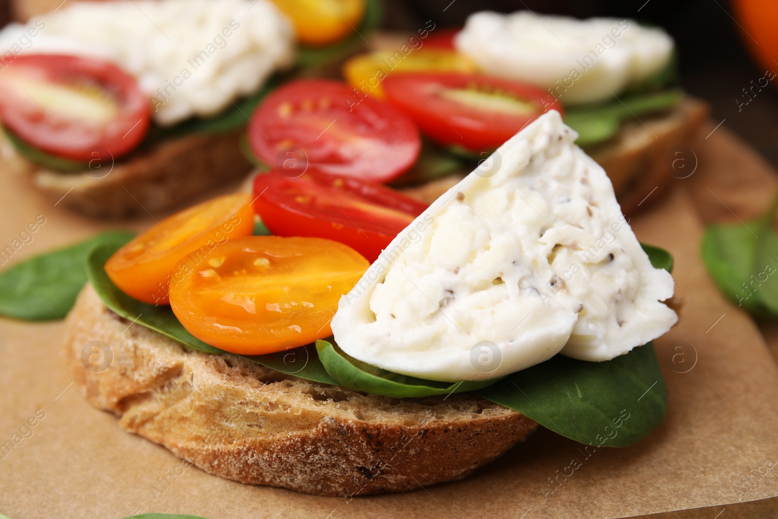 Photo of Delicious sandwich with burrata cheese and tomatoes on board, closeup