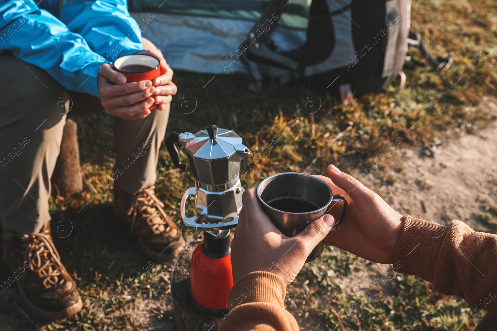 Photo of Young couple drinking coffee near camping tents outdoors, closeup