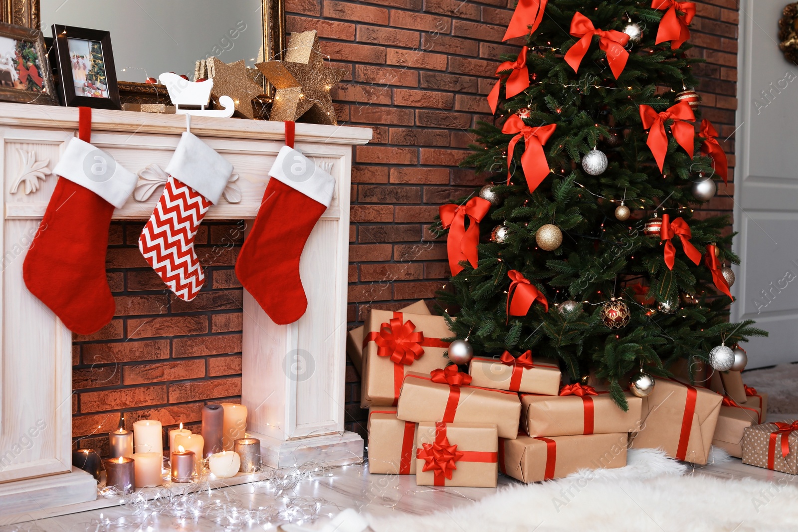 Photo of Beautiful Christmas tree and gifts near decorative fireplace with stockings indoors