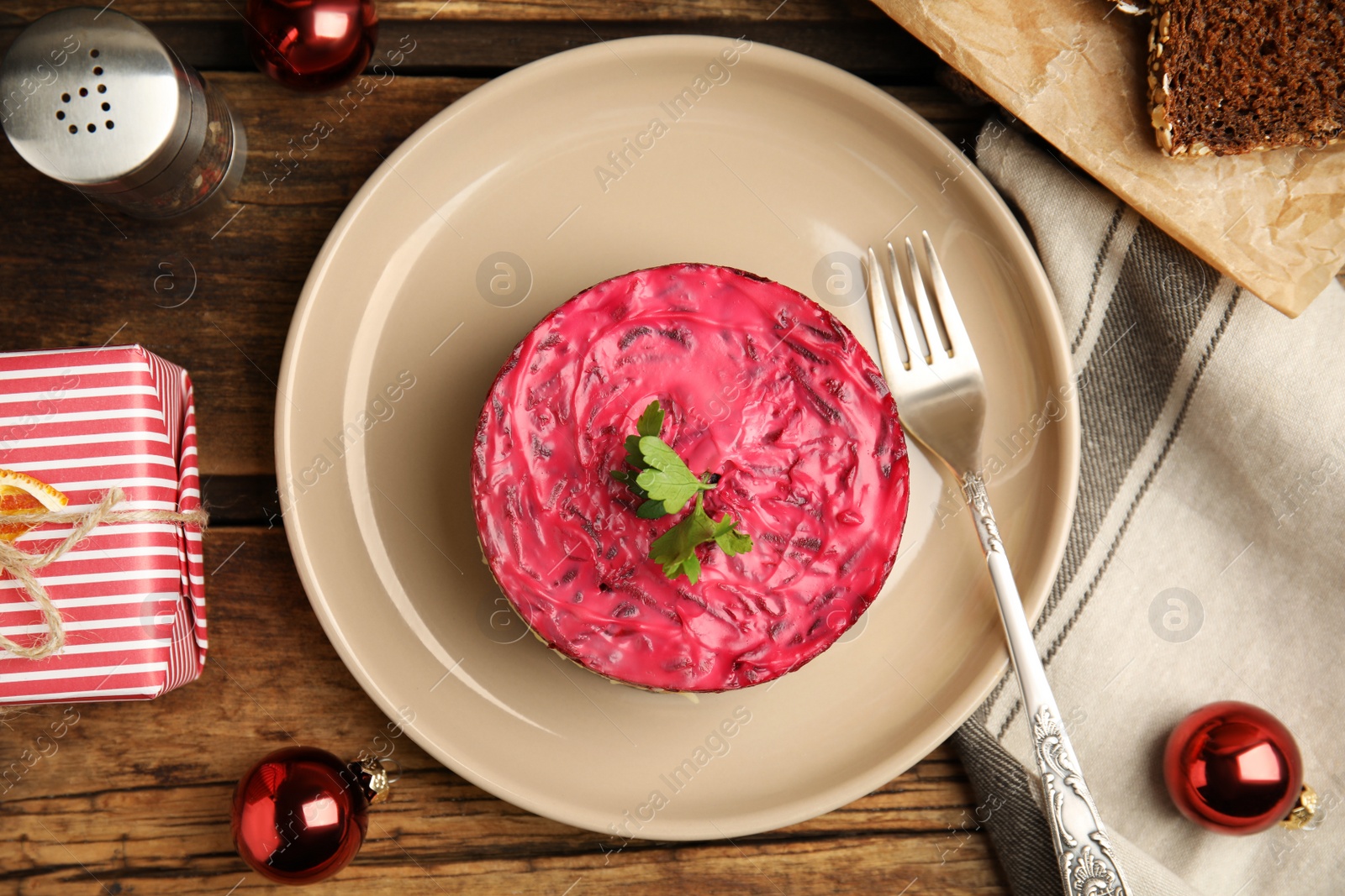 Photo of Herring under fur coat served on wooden table, flat lay. Traditional russian salad