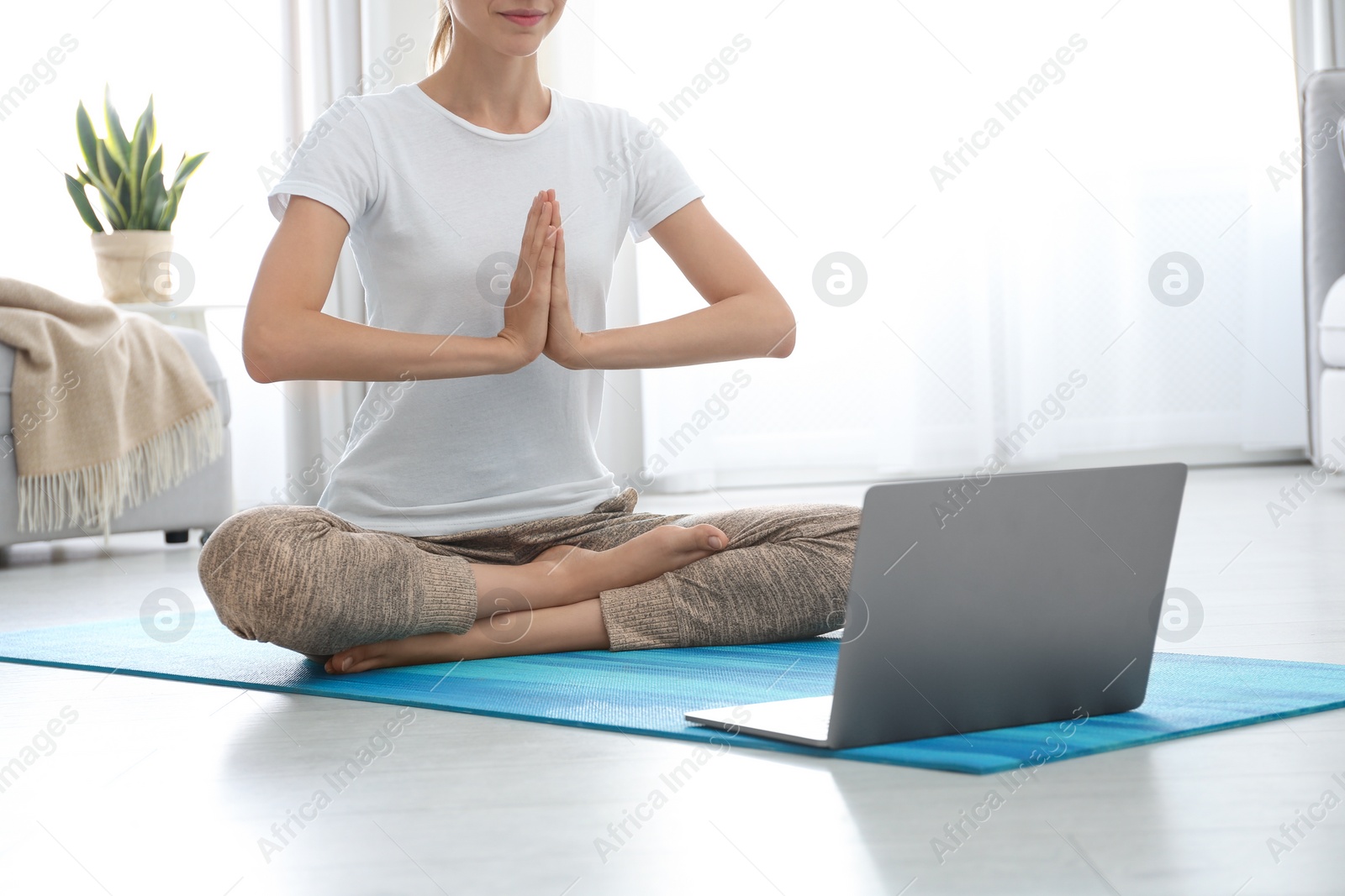 Photo of Woman having online video class via laptop at home, closeup. Distance yoga course during coronavirus pandemic