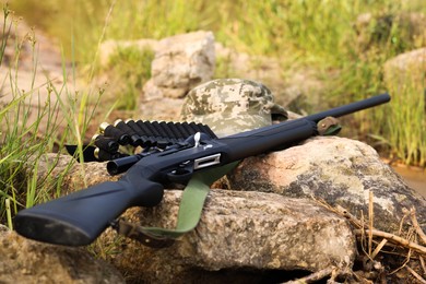 Hunting rifle and cartridges on rocks outdoors