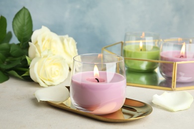 Photo of Burning candles in glass holders and roses on light table