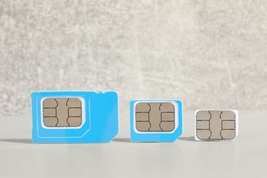Photo of Different color SIM cards on light grey table. Space for text