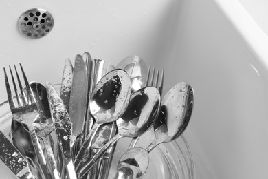 Photo of Washing silver spoons, forks and knives in kitchen sink, above view