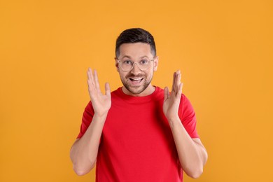 Portrait of emotional man in stylish glasses on yellow background