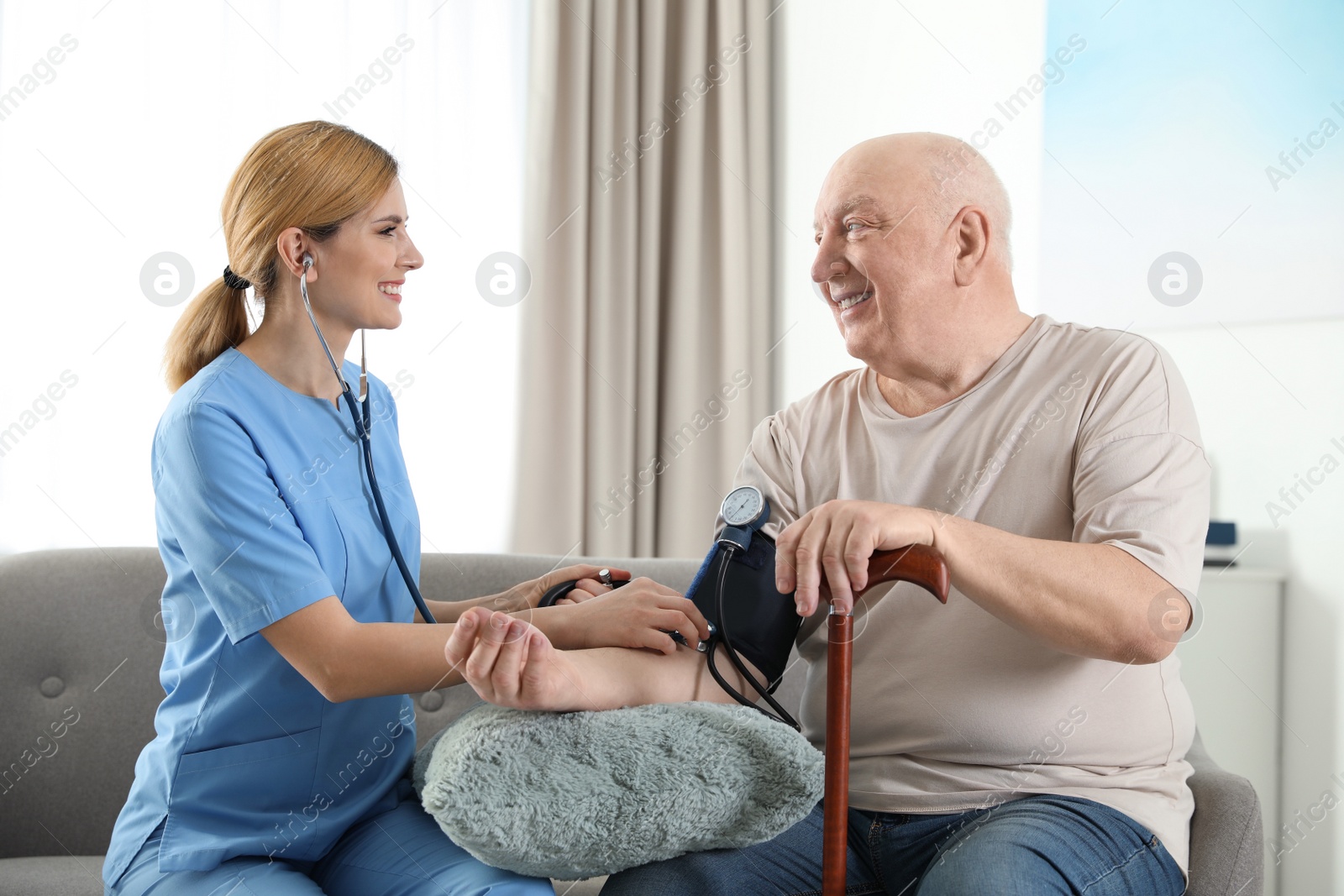 Photo of Nurse measuring blood pressure of elderly man indoors. Assisting senior people