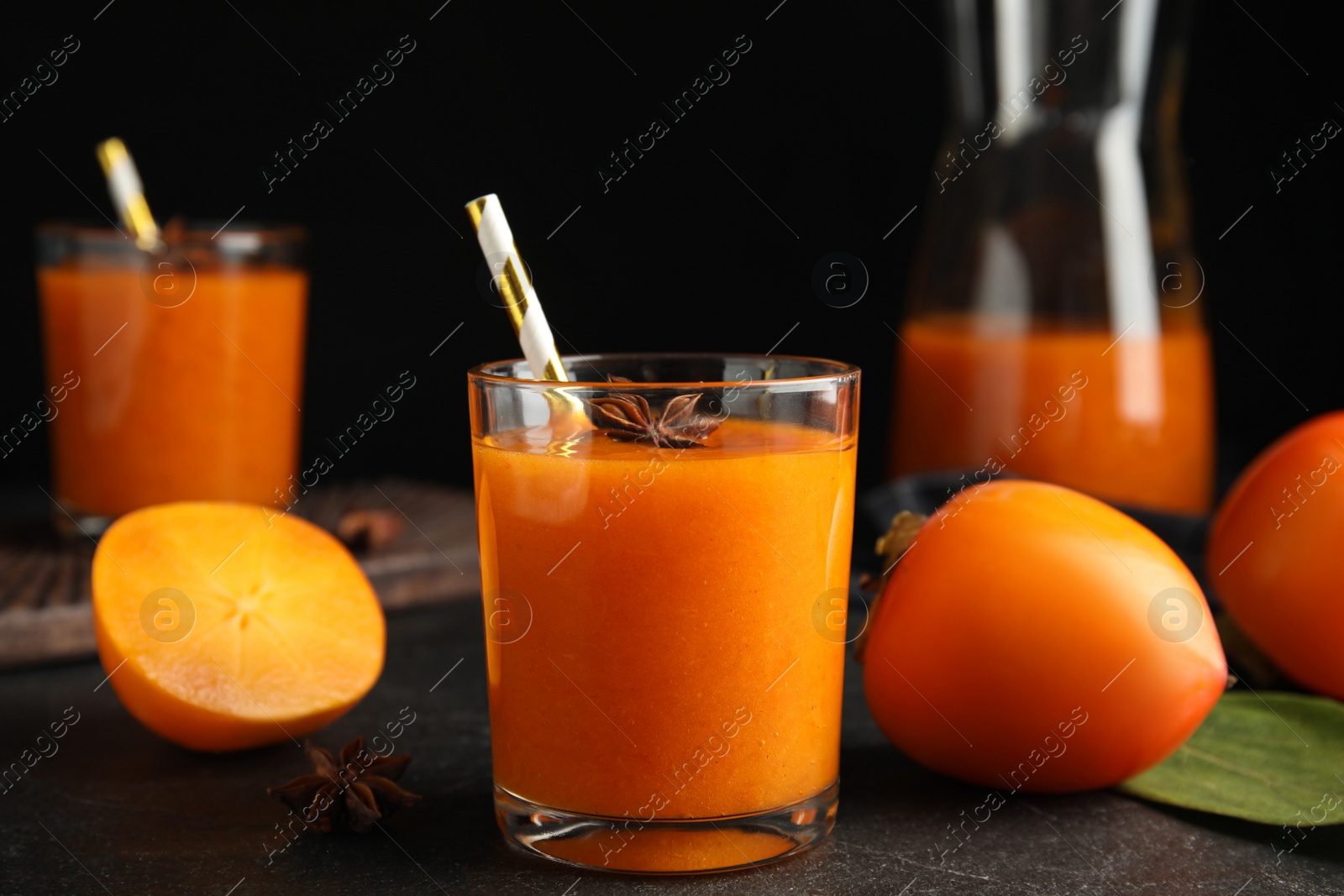 Photo of Tasty persimmon smoothie with anise and fresh fruits on black table