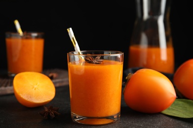 Photo of Tasty persimmon smoothie with anise and fresh fruits on black table