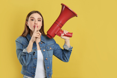Photo of Young woman with megaphone on yellow background