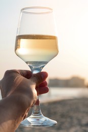 Photo of Woman holding glasstasty wine near sea, closeup