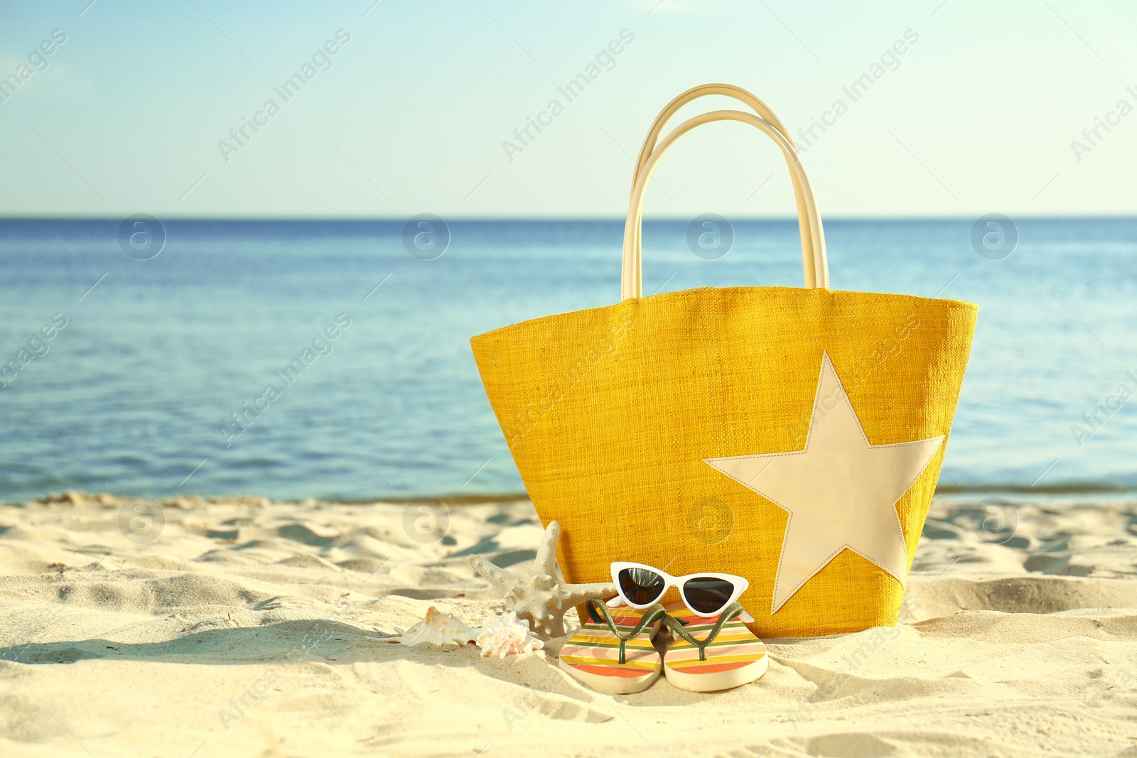 Photo of Composition with stylish beach accessories on sand near sea. Space for text