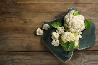Photo of Cut and whole cauliflowers on wooden table, top view. Space for text