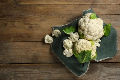 Cut and whole cauliflowers on wooden table, top view. Space for text