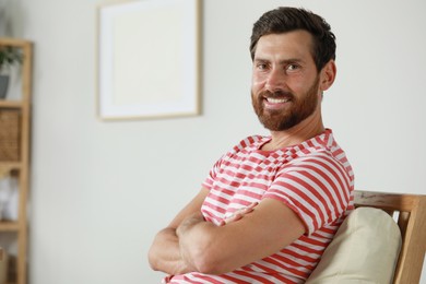 Photo of Portrait of handsome bearded man in armchair at home, space for text