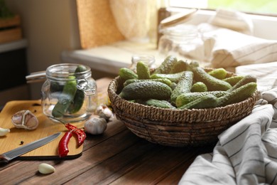 Fresh cucumbers, other ingredients and jar on wooden table. Pickling vegetables