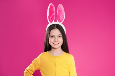 Photo of Portrait of little girl in Easter bunny ears headband on color background