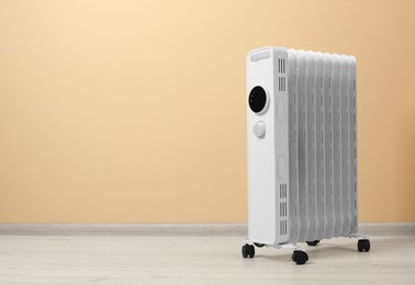 Photo of Modern portable electric heater on floor near beige wall indoors, space for text