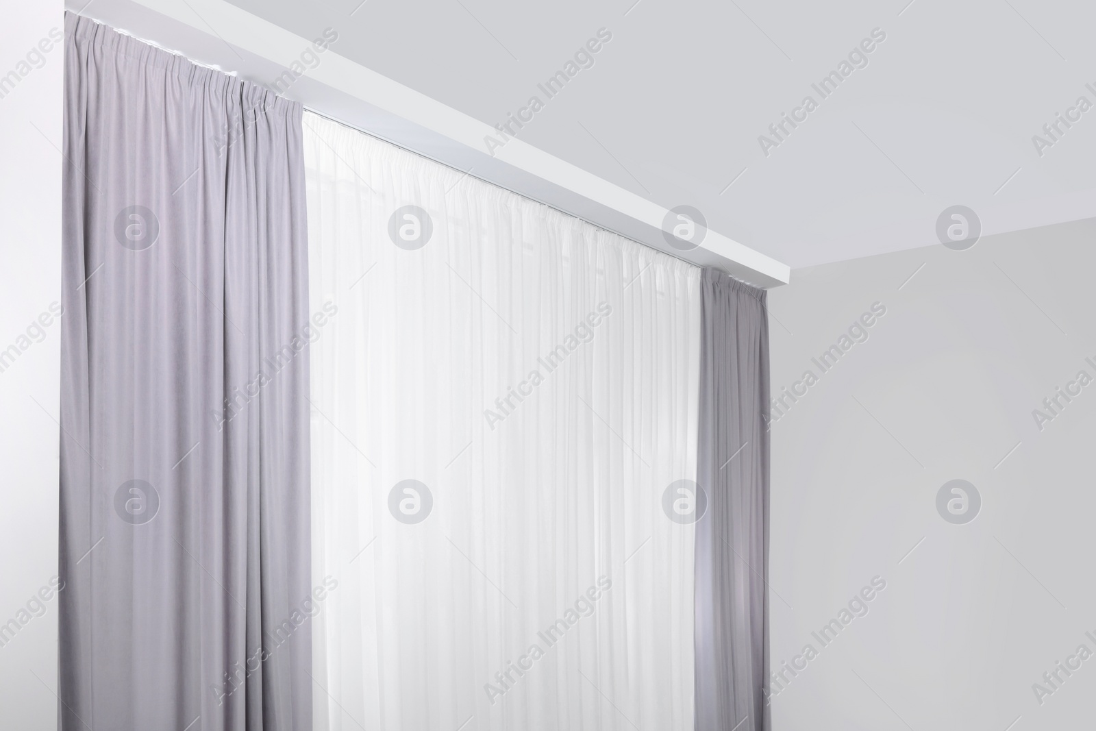 Photo of Light grey window curtains and white tulle indoors