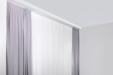 Photo of Light grey window curtains and white tulle indoors