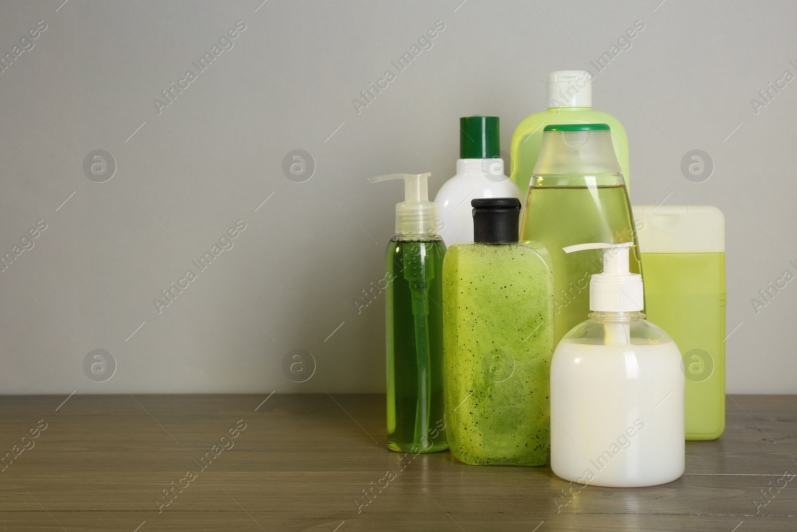 Photo of Different shower gel bottles on wooden table. Space for text