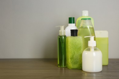 Photo of Different shower gel bottles on wooden table. Space for text