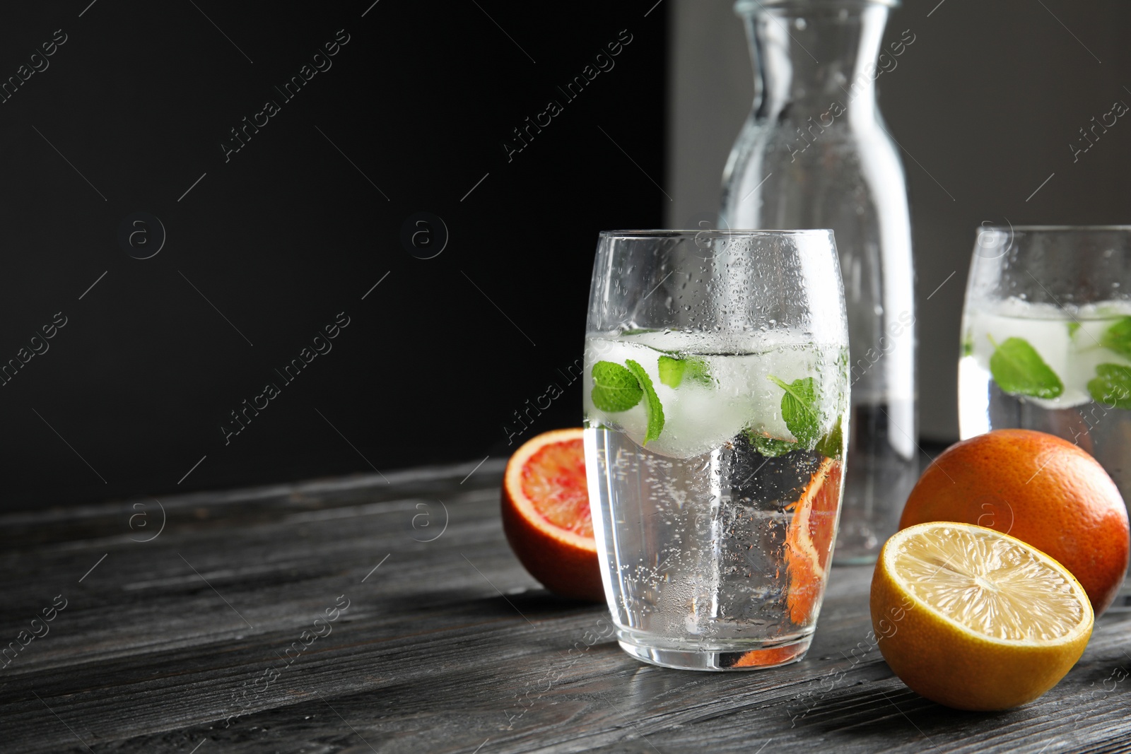 Photo of Composition with refreshing drink with mint and ice cubes in glass on dark table. Space for text