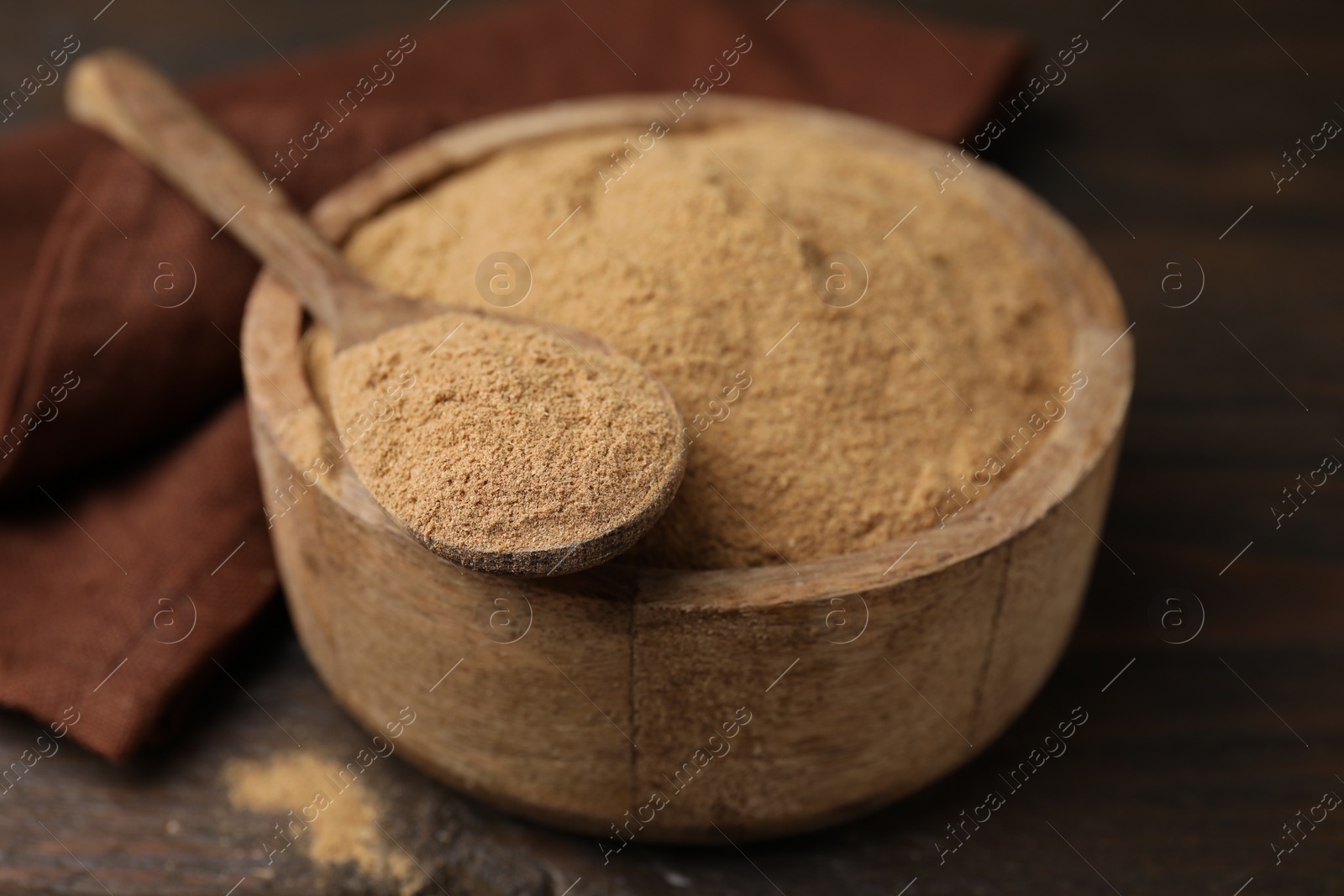 Photo of Dietary fiber. Psyllium husk powder in bowl and spoon on wooden table, closeup