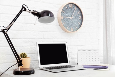 Stylish workplace with lamp and laptop on table