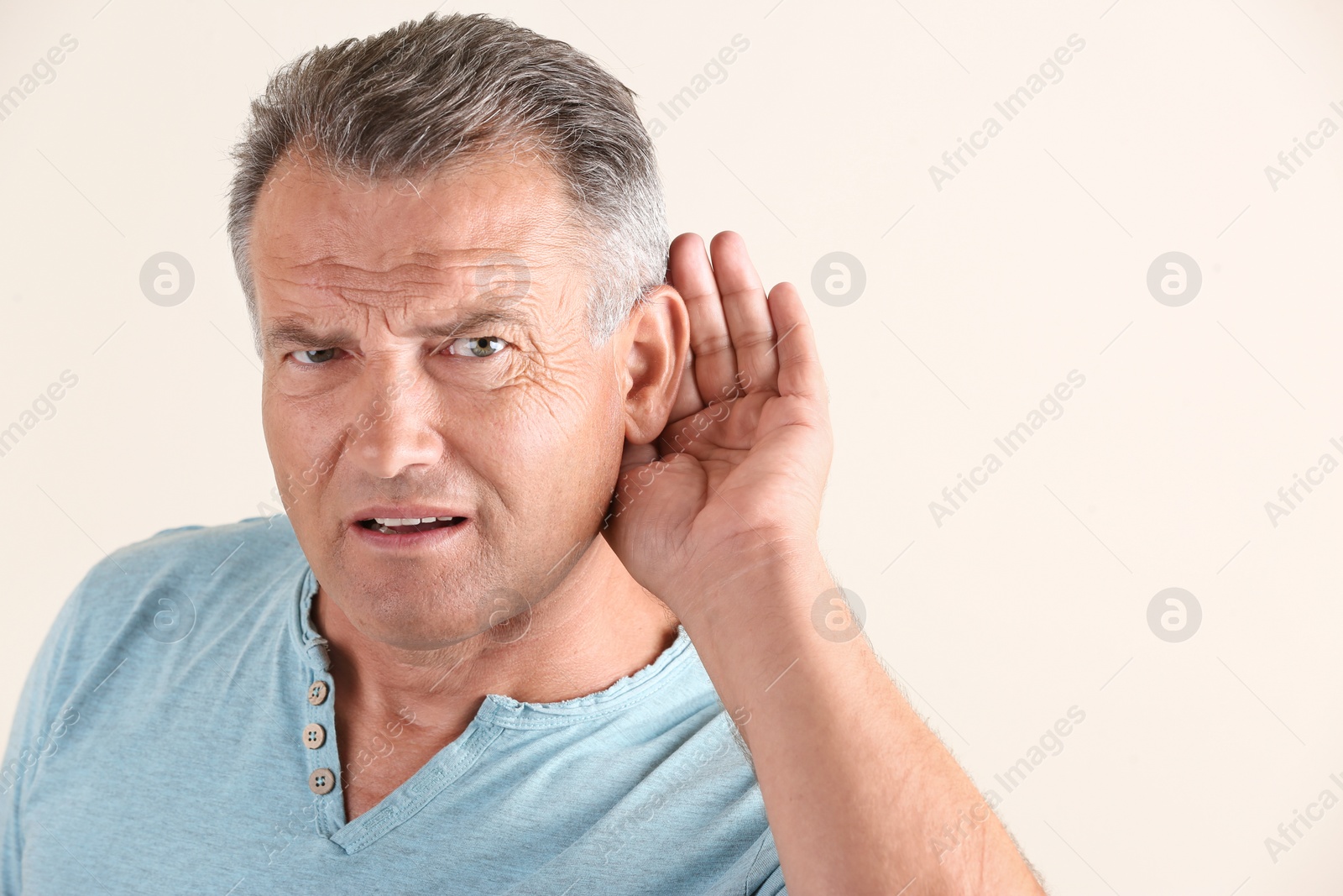 Photo of Mature man with hearing problem on light background