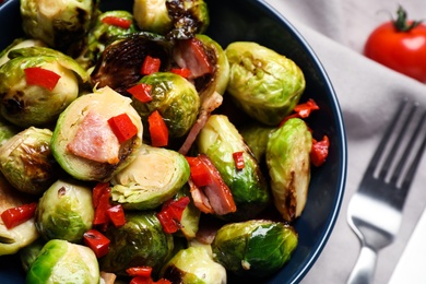 Photo of Delicious Brussels sprouts with bacon in bowl, closeup