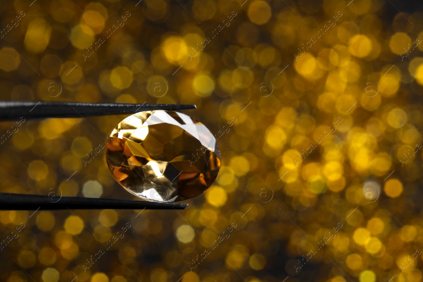 Photo of Tweezers with beautiful gemstone on blurred background, closeup. Space for text