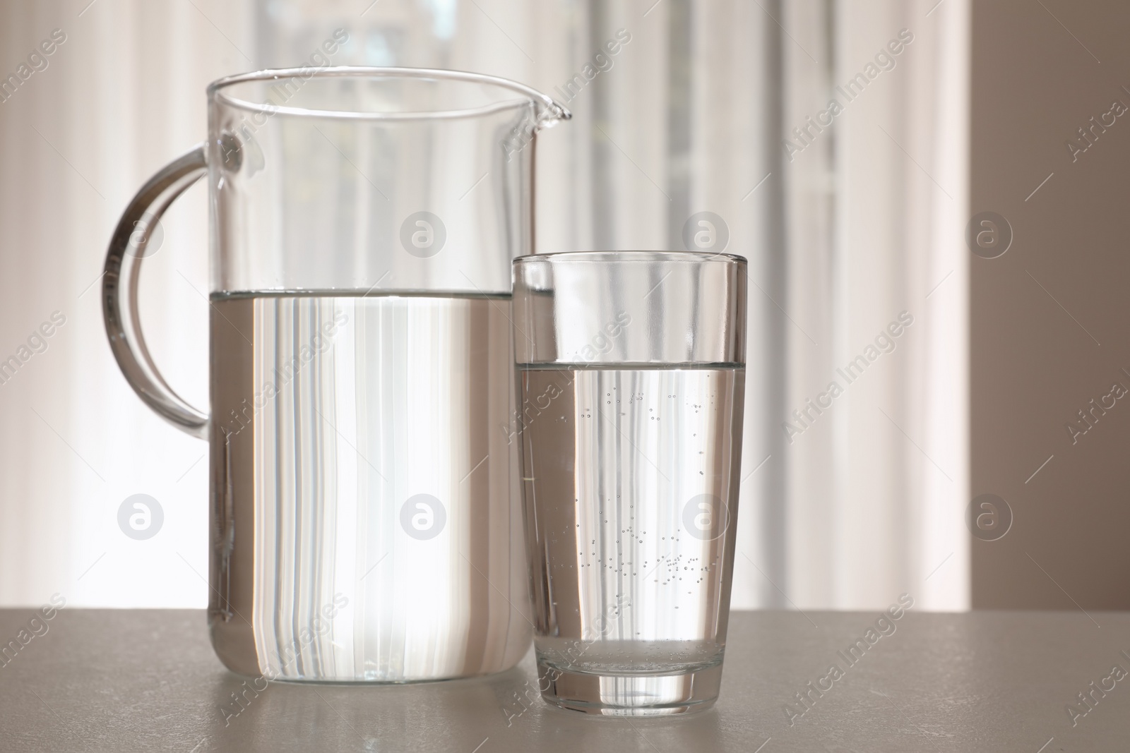 Photo of Jug and glass with water on table indoors