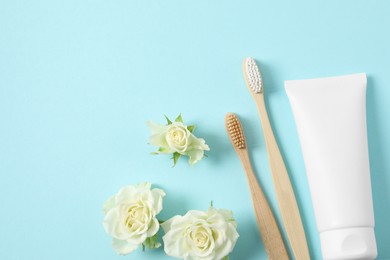 Photo of Flat lay composition with toothbrushes, toothpaste and flowers on turquoise background. Space for text