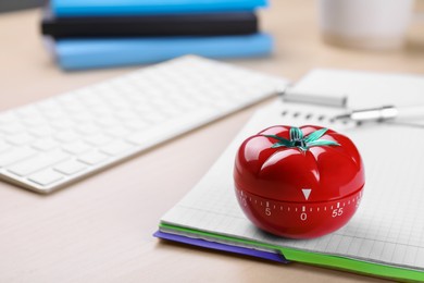 Photo of Kitchen timer in shape of tomato and notebook on wooden table, space for text