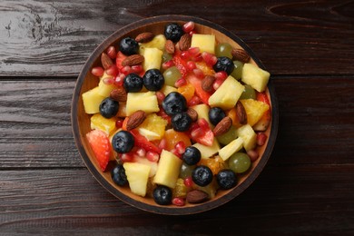 Delicious fruit salad in bowl on wooden table, top view