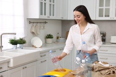 Photo of Smiling woman separating garbage in kitchen. Space for text
