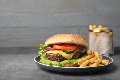 Photo of Delicious burger and french fries served on grey table. Space for text