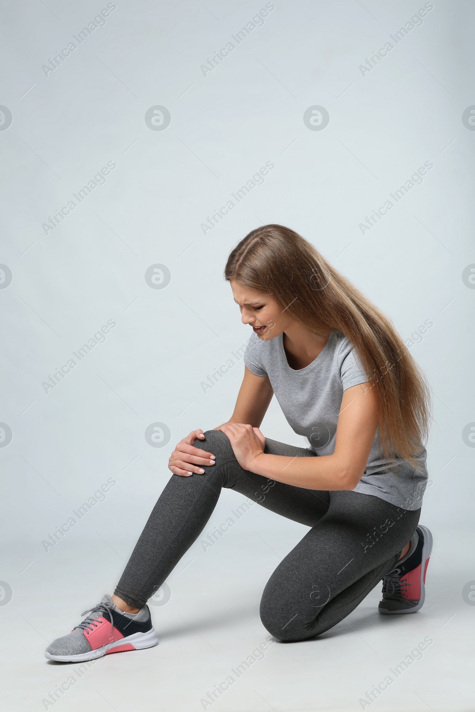 Photo of Full length portrait of sportswoman having knee problems on grey background